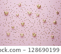 Golden heart shapes and small beads scattered on soft pastel pink background for romantic mood 128690199