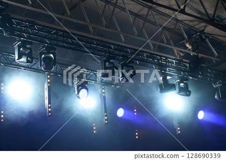 Stage with bright concert lighting, spotlights and smoke effects prepared for live music performance. Illumination for music event 128690339
