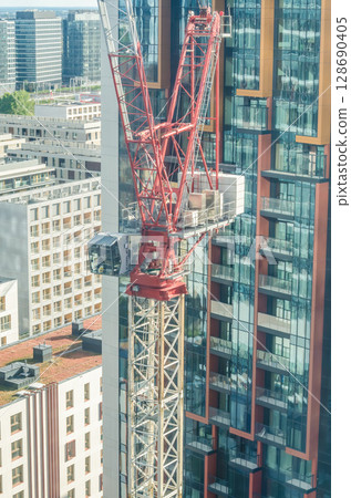 Red crane beside high-rise glass and steel buildings. High quality photo Red crane beside high-rise glass and steel buildings. High quality photo 128690405