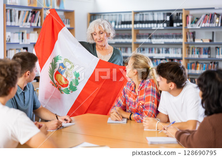 Mature female teacher shows scholchildren the national flag of Peru 128690795