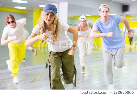 Teenage girl in cap training breakdance Toprock moves in dance hall Teenage girl in cap training breakdance Toprock moves in dance hall 128690800