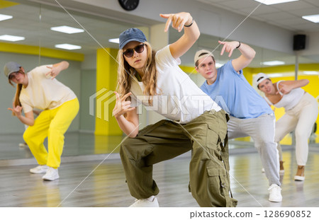 Boy and girls dancing synchronous group choreography in dance hall Boy and girls dancing synchronous group choreography in dance hall 128690852