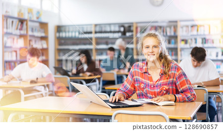 Portrait of diligent college girl studying using laptop Portrait of diligent college girl studying using laptop 128690857