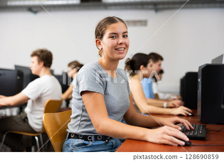 Positive girl using computer in classroom Positive girl using computer in classroom 128690859