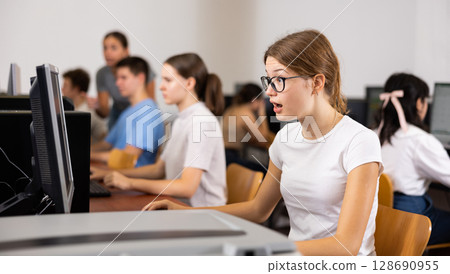 Focused female student in glasses using PC and studying computer science in the classroom 128690955