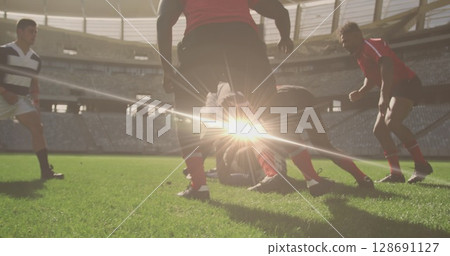 Image of spots lights moving over diverse team of rugby players during game in field 128691127