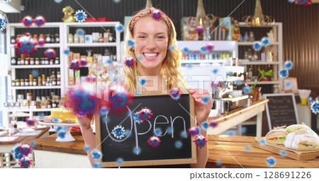 Barista holding open sign in artisanal cafe, with counter and pastries, coronavirus graphics Barista holding open sign in artisanal cafe, with counter and pastries, coronavirus graphics 128691226