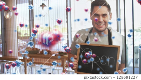 Smiling Chinese man holding chalkboard sign reading Open in cafe, with virus particles, copy space 128691227