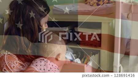 Image of usa flag over happy caucasian mother and baby searching clothes 128691416