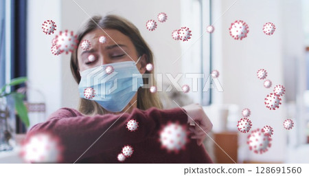 Woman wearing burgundy sweater coughing into elbow in office, with surgical mask and virus overlays Woman wearing burgundy sweater coughing into elbow in office, with surgical mask and virus overlays 128691560