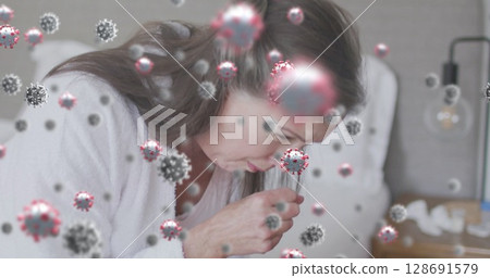 Woman wearing bathrobe blowing nose into tissue in bedroom, with tissue box, coronavirus particles Woman wearing bathrobe blowing nose into tissue in bedroom, with tissue box, coronavirus particles 128691579