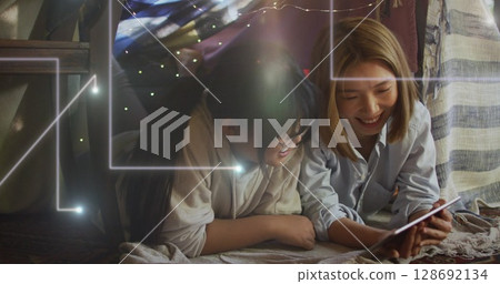 Image of lights falling over happy asian mother and daughter using tablet Image of lights falling over happy asian mother and daughter using tablet 128692134