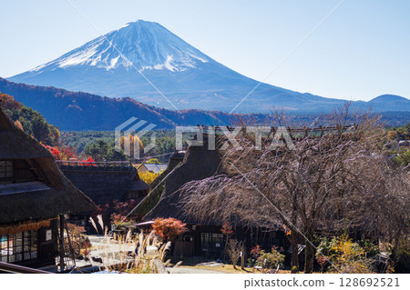 Mount Fuji in the early autumn morning through an old thatched roof house Mount Fuji in the early autumn morning through an old thatched roof house 128692521