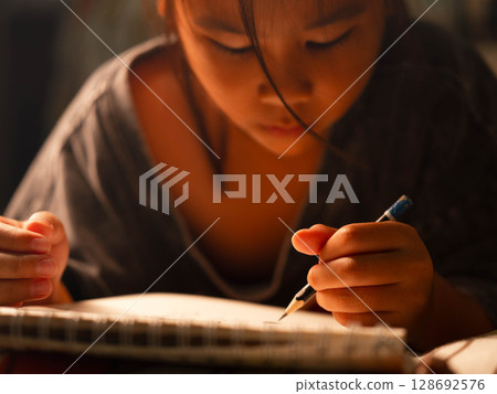 Close up of cute asian girl hand holding pencil drawing on white paper at home. Close up of cute asian girl hand holding pencil drawing on white paper at home. 128692576