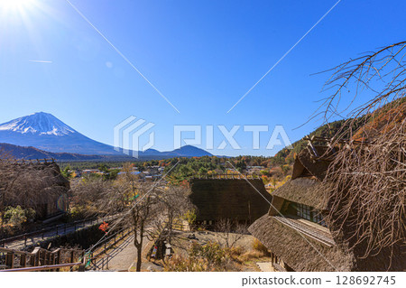 Mount Fuji in the early autumn morning through an old thatched roof house Mount Fuji in the early autumn morning through an old thatched roof house 128692745