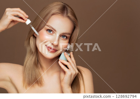 Young beautiful woman applying face serum 128692794
