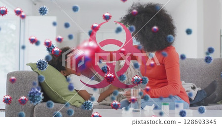 Image of virus cells and biohazard symbol over african american mother with sick son Image of virus cells and biohazard symbol over african american mother with sick son 128693345