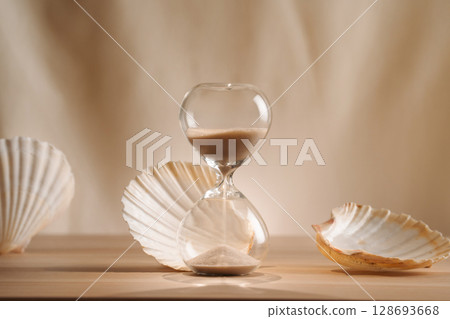 A sophisticated display featuring a delicate hourglass surrounded by elegant seashells, emphasizing the blend of minimalism, creative design, and coastal aesthetics for unique and timeless concept 128693668