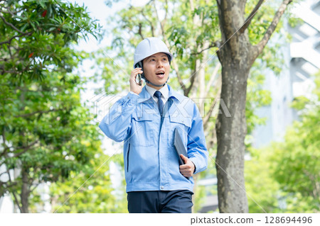 Middle-aged man in work clothes walking with smartphone 128694496