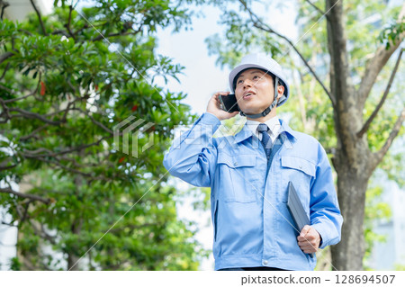 身穿工作服的中年男子拿著智慧型手機走路 128694507