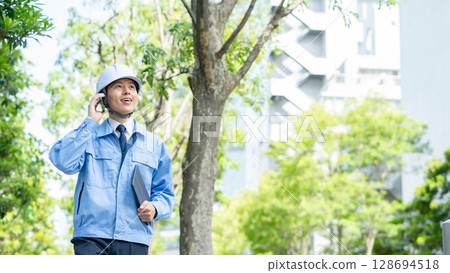Middle-aged man in work clothes walking with smartphone 128694518