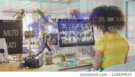 Image of financial data over biracial businesswoman working on computer in office 128694634