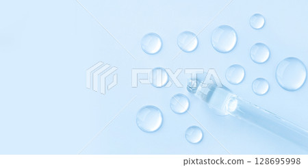Drop of cosmetics and a pipette on a blue background. A product for skin, face or hair care. Drop of cosmetics and a pipette on a blue background. A product for skin, face or hair care. 128695998