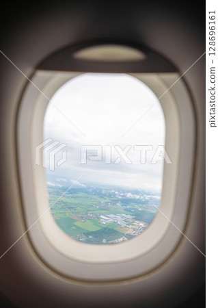 Aerial view of landscape seen through an airplane window during flight. Travel perspective, distance observation, and skybound experience. 128696161