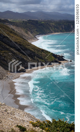 A breathtaking aerial view of a rugged coastline in Asturias, Spain, showcasing dramatic cliffs plunging into the vibrant turquoise waters of the Cantabrian Sea. A breathtaking aerial view of a rugged coastline in Asturias, Spain, showcasing dramatic cliffs plunging into the vibrant turquoise waters of the Cantabrian Sea. 128696650