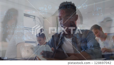 Image of math formulas moving over african american boy with tablet and class of diverse pupils 128697042