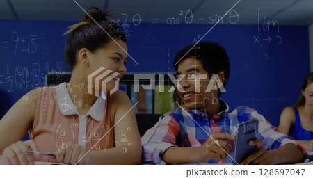 Image of math formulas moving over happy diverse boy and girl using smartphone at school 128697047