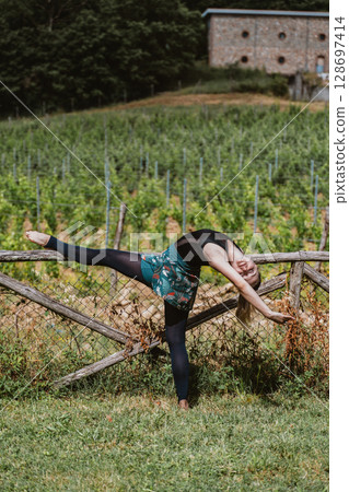Ballerina Performing Graceful Stretch in Vineyard Setting Ballerina Performing Graceful Stretch in Vineyard Setting 128697414