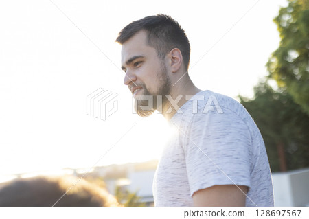 Young man enjoying sunlight in urban setting during golden hour 128697567