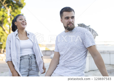 Cheerful young woman laughing with pensive young man outdoors Cheerful young woman laughing with pensive young man outdoors 128697583