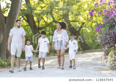 Happy family walking in park holding hands on summer day Happy family walking in park holding hands on summer day 128697645