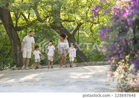 Happy family walking in park enjoying sunny day 128697648