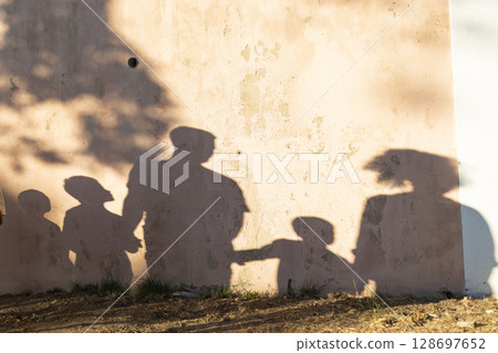 Family silhouette projected on wall during golden hour 128697652