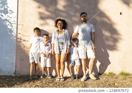 Happy family posing together against pink wall 128697672