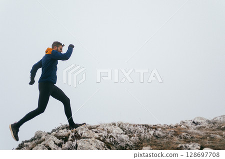 Man Climbing Rocky Hill in Fog 128697708