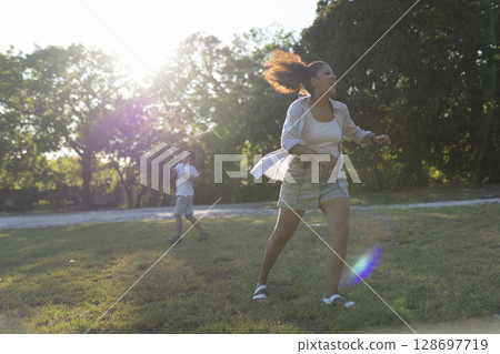 Happy mother running and playing with her son in a sunny park during summer Happy mother running and playing with her son in a sunny park during summer 128697719