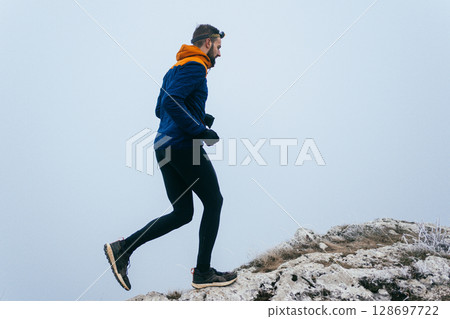 Man Climbing Rocky Hill in Fog Man Climbing Rocky Hill in Fog 128697722
