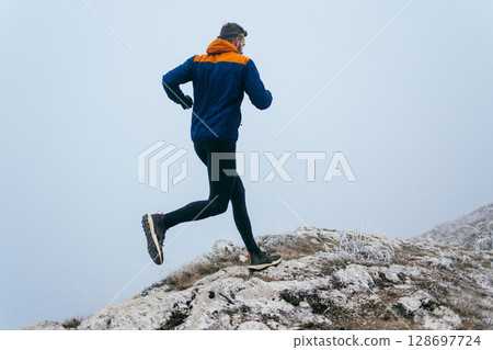 Man Climbing Rocky Hill in Fog Man Climbing Rocky Hill in Fog 128697724