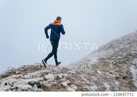 Man Climbing Rocky Hill in Fog 128697731