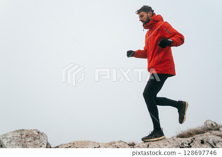 Man Climbing Rocky Hill in Fog 128697746
