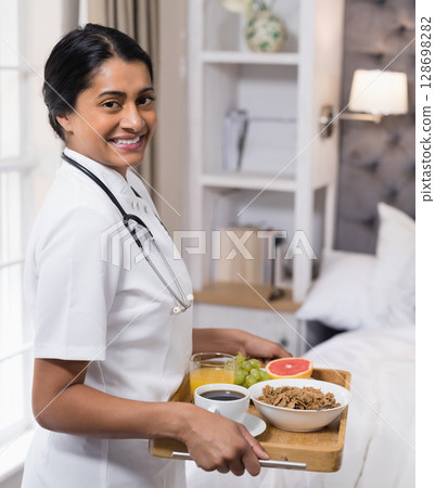 Smiling nurse serving healthy breakfast in cozy bedroom, promoting wellness care Smiling nurse serving healthy breakfast in cozy bedroom, promoting wellness care 128698282