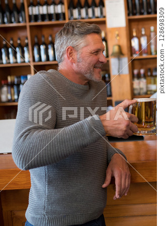 Man enjoying beer at bar, smiling and relaxing in cozy atmosphere 128698309
