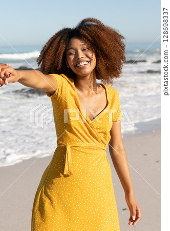 Smiling woman in yellow dress enjoying sunny day on tropical beach 128698337
