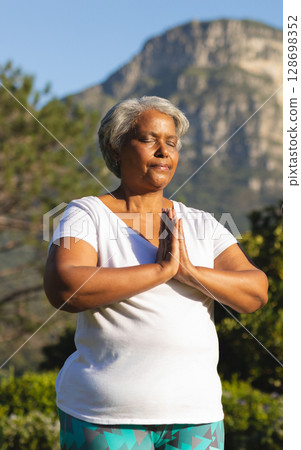 Meditating outdoors, senior woman finding peaceful moment in nature's serenity 128698352