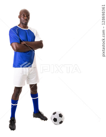Confident soccer player standing with arms crossed next to soccer ball, copy space 128698361