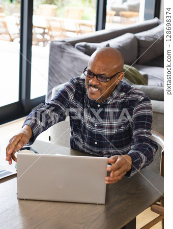 Smiling man using laptop at home, enjoying video call with family 128698374